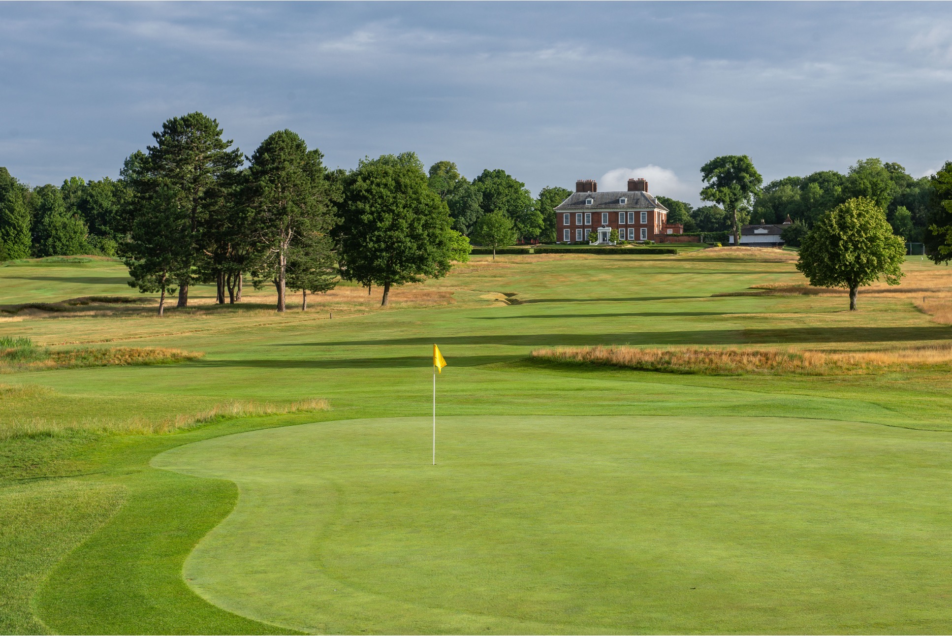 Expansive view of a lush green golf course fairway under a clear morning sky